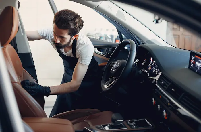 Tehnician curatand pielea si lustruind caroseria unui autoturism